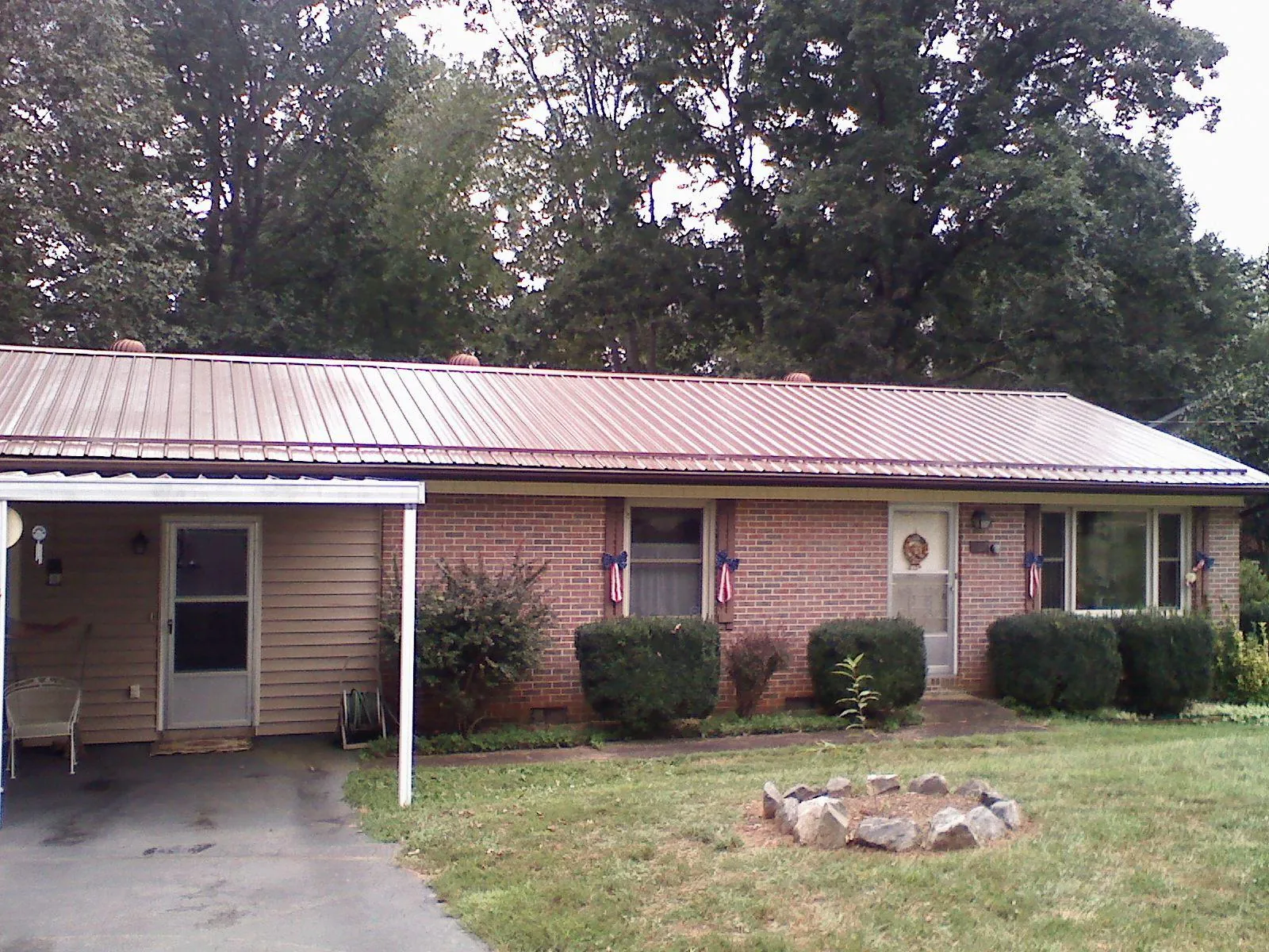 Bronze metal roof and carport on a brick ranch home — Roof Repair work by our crew in Bennett